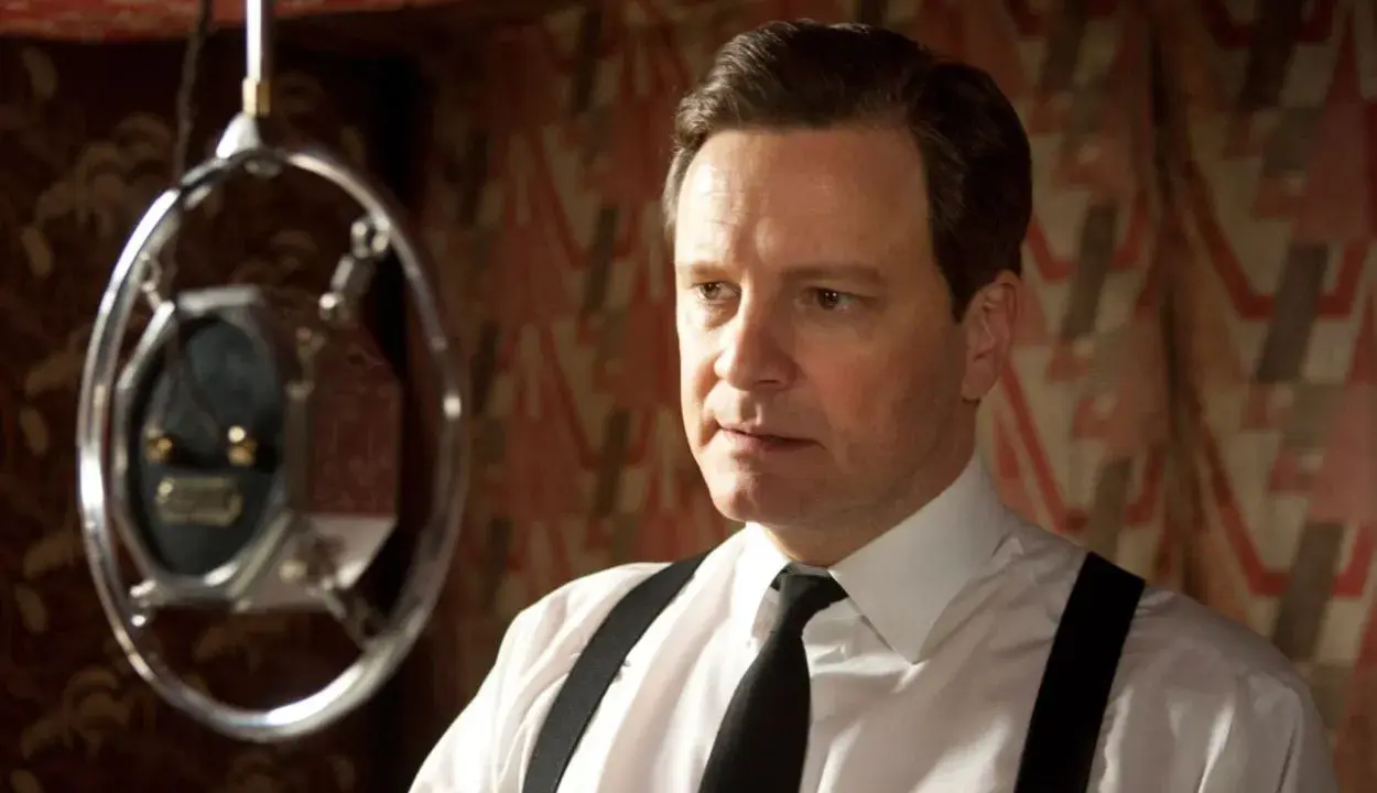 Colin Firth i en vit skjorta med hängslen och slips, nära en mikrofon. En scen från filmer och tv-program med Colin Firth.