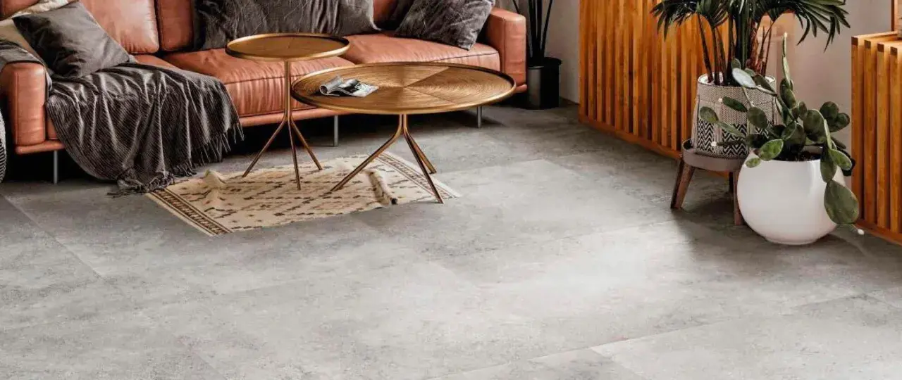 Un elegante soggiorno con divano in pelle color caramello, tavolini dorati e un tappeto etnico su un **pavimento grigio** che crea **abbinamenti** moderni e sofisticati.
