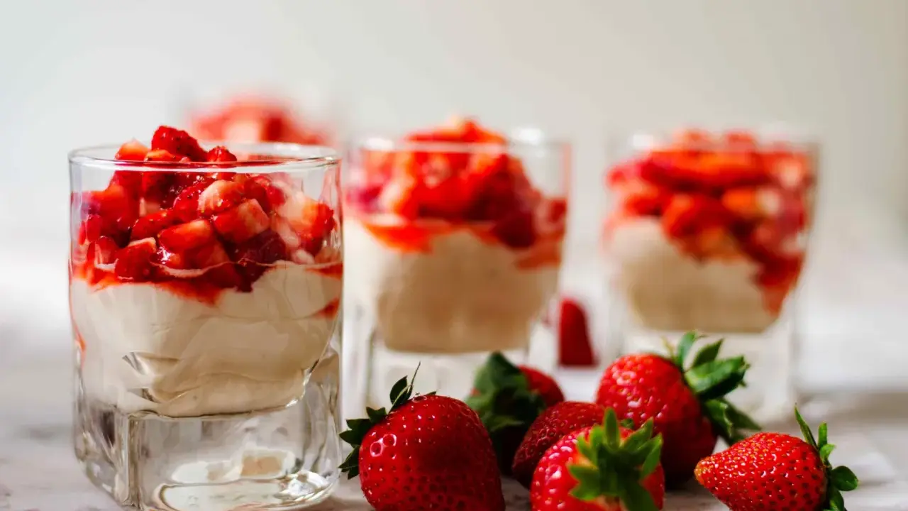 Enkel dessert med jordgubbar i glas, toppad med färska jordgubbar och en krämig fyllning. Perfekt för en sommardag.