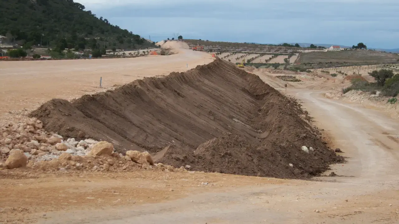 Un terraplén, parte de una obra vial, se eleva con tierra removida. El terraplén significado es la elevación artificial del terreno.
