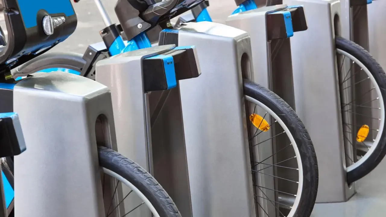 Des vélos bleus et gris sont rangés, prêts à recharger sur une borne auto.