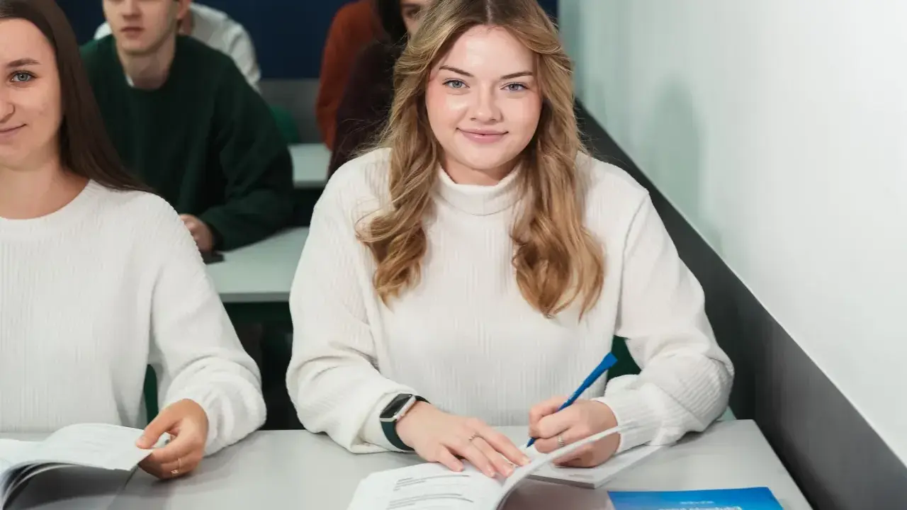 Uśmiechnięta studentka pisze w zeszycie, idealne zdjęcie do legitymacji.