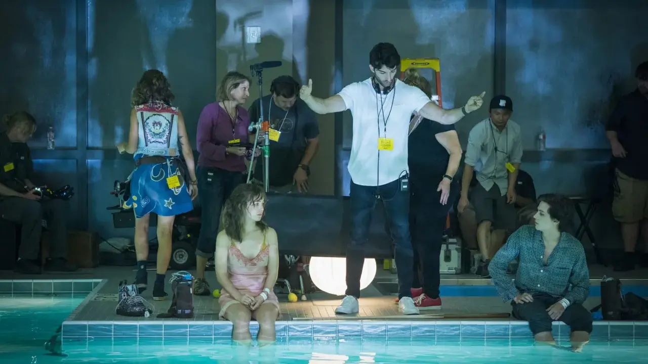 Reżyser instruuje aktorkę siedzącą w basenie. Wszyscy są **trzy kroki od siebie**, tworząc scenę filmową.