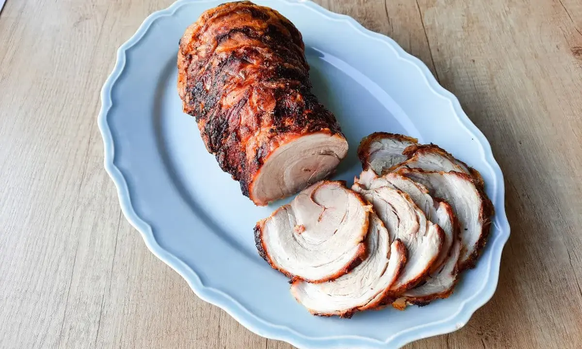 Soczysta rolada z boczku, pieczona do perfekcji, podana na błękitnej paterze. Idealna na rodzinny obiad.