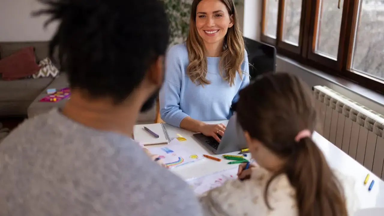 Lehrerin bespricht mit Eltern und Kind Fortschritte. Eine Elternsprechtag Vorlage für Lehrer könnte hier nützlich sein.