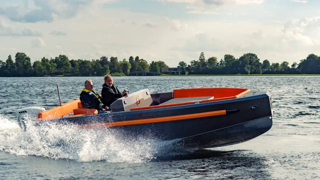 Deux hommes naviguent sur un bateau rapide, créant des éclaboussures. Le design moderne du bateau, avec ses accents orange vif, suggère une conception soignée, peut-être pour fabriquer des flaps pour bateau.
