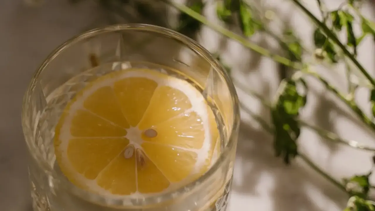 Ett glas med vatten och en citronskiva, perfekt för varma sommardagar. Enkel och uppfriskande bland sommar drinkar.