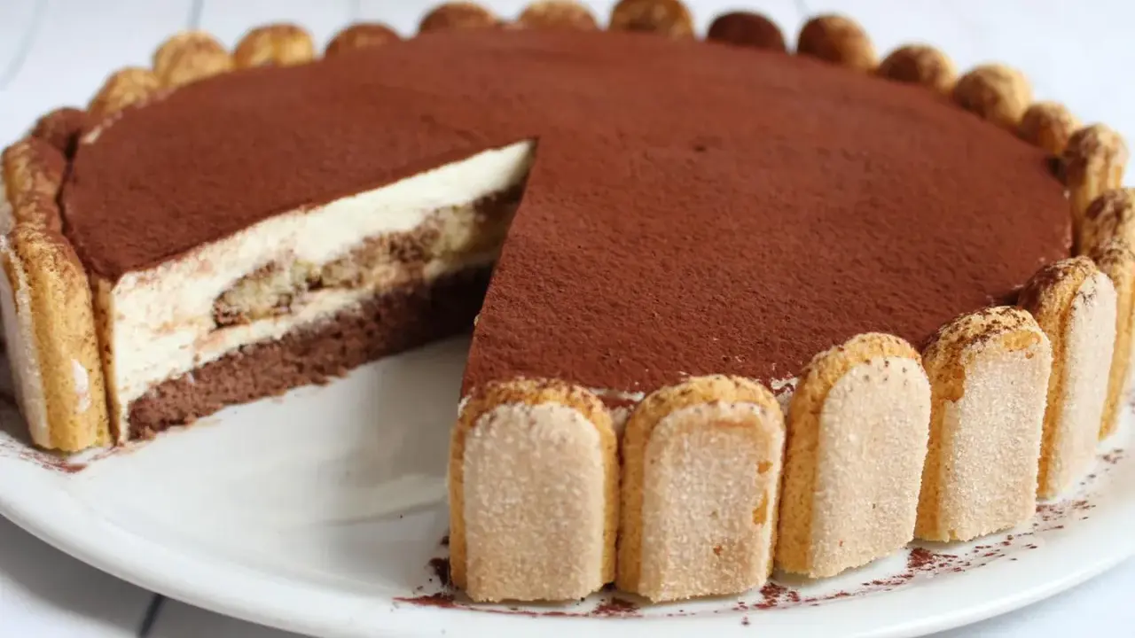 Eine köstliche tiramisu torte, mit Löffelbiskuits und Kakaopulver verziert, wartet darauf, angeschnitten zu werden.