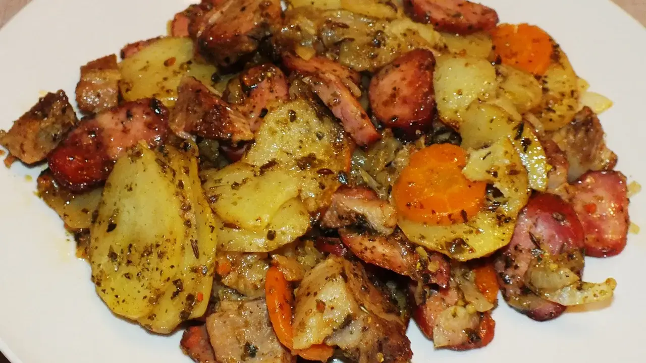 Pyszne duszonki z piekarnika: ziemniaki, kiełbasa i marchewka, doprawione ziołami.