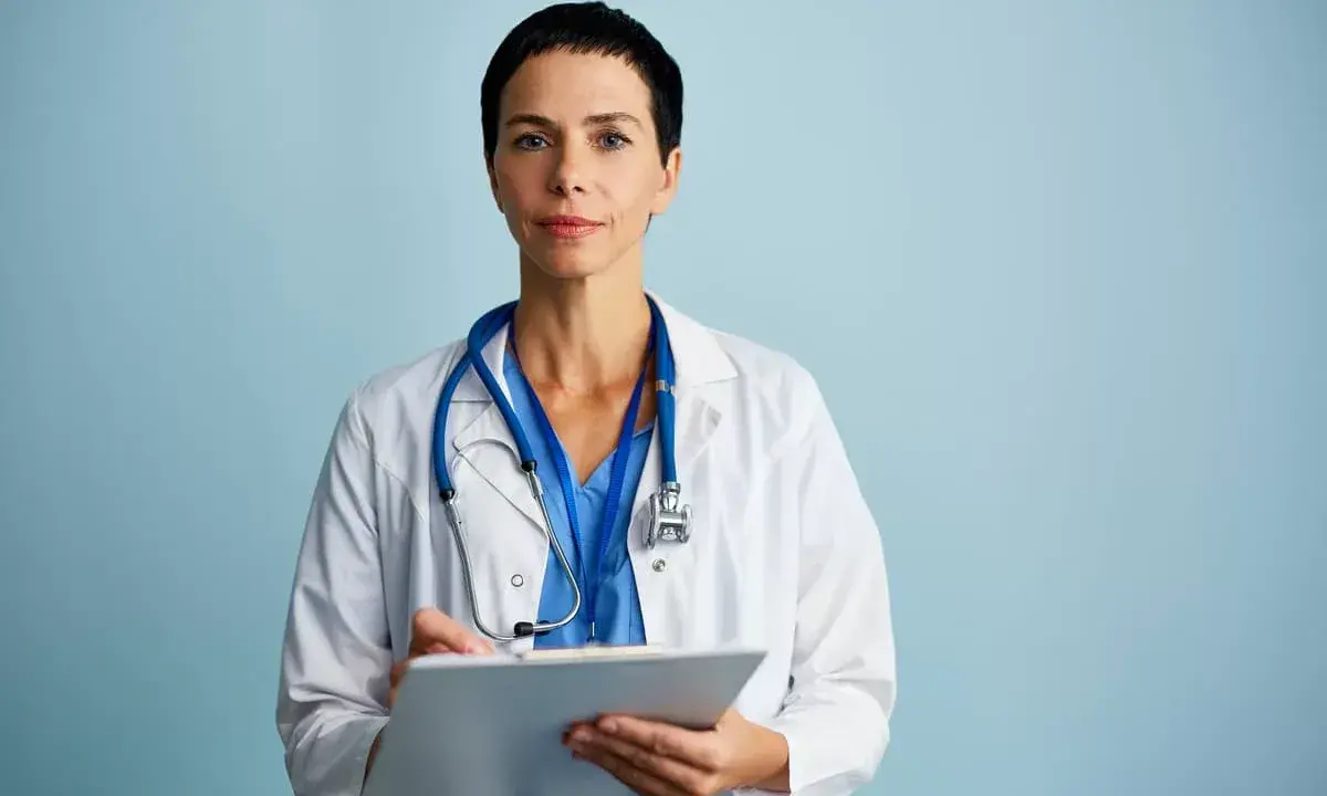 Medico con camice bianco e stetoscopio, appunti su cartella clinica. Ricerca sulla sindrome di Laron.