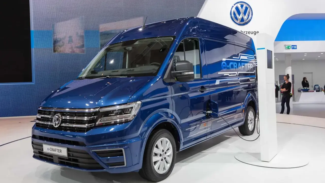 Niebieski kamper elektryczny e-Crafter podłączony do ładowarki na stoisku Volkswagena.