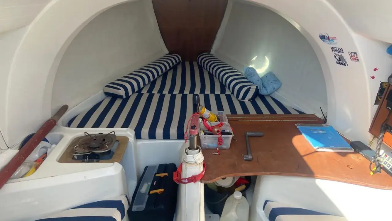 Intérieur du first 210, avec banquettes rayées bleu et blanc, réchaud, outils et bidon d'eau. Prêt pour l'aventure !