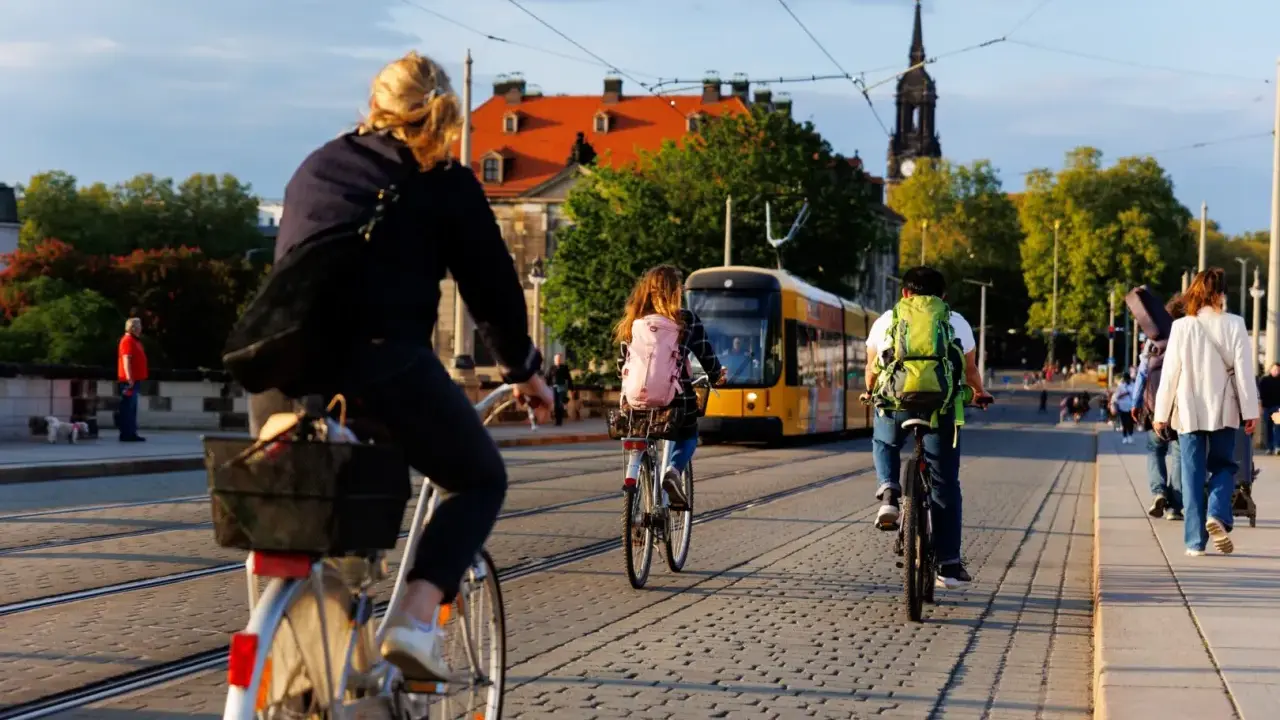 Menschen radeln durch eine Stadt in Deutschland, ein gelber Tram fährt vorbei. Perfekt für Bikepacking Deutschland!