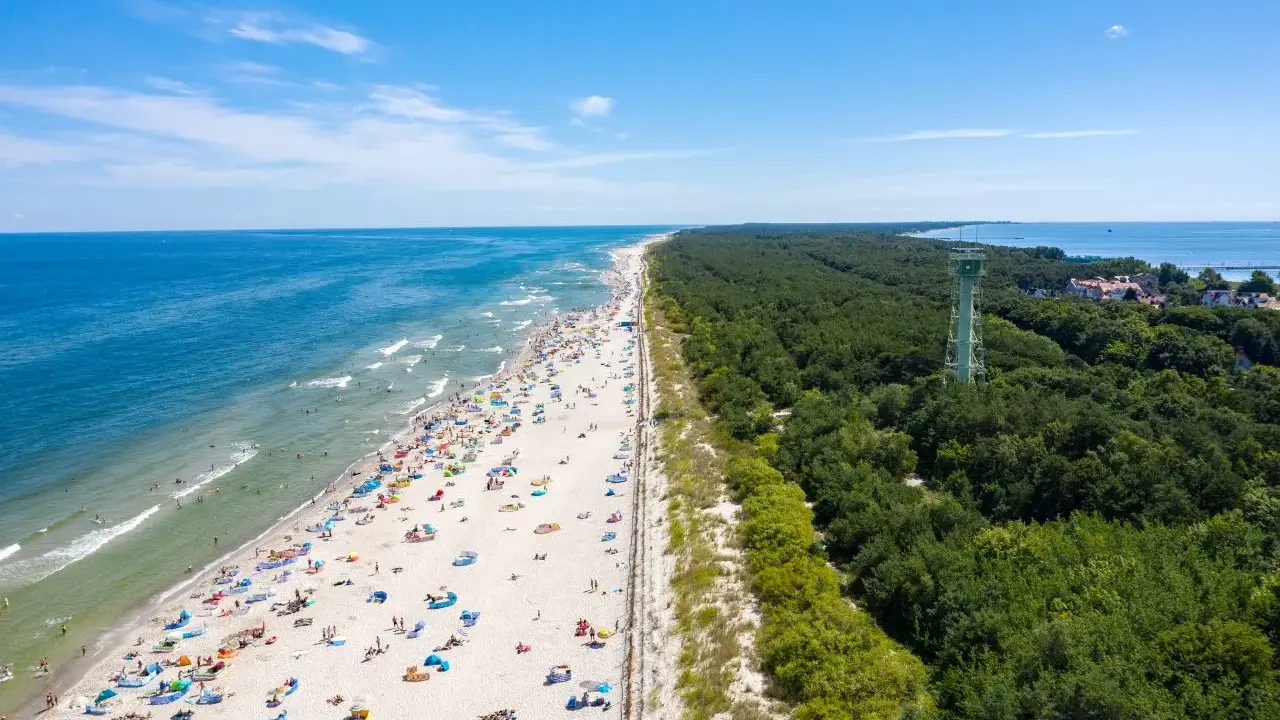 Słoneczna plaża pełna ludzi, las i wieża widokowa – to jedne z wielu **ciekawych miejsc na Pomorzu**.