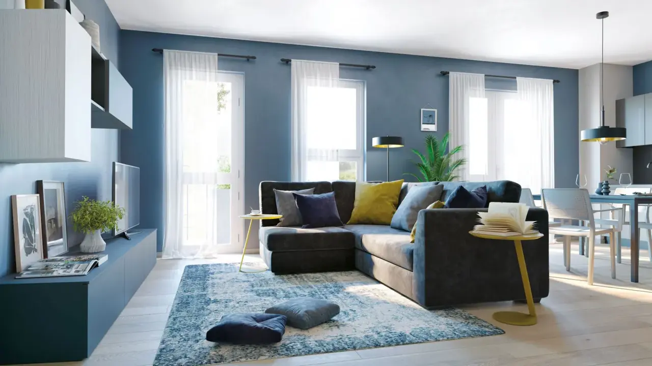 Un soggiorno moderno con divano angolare grigio scuro, cuscini blu e gialli, tappeto blu e bianco. Le pareti blu creano un'atmosfera rilassante, dimostrando che blu e grigio stanno bene insieme.