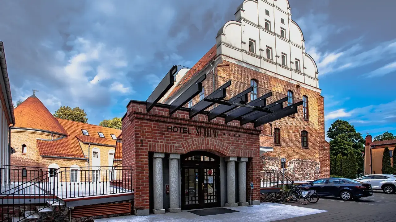 Hotel St. Bruno w Giżycku, dawniej zamek krzyżacki, z charakterystyczną ceglaną fasadą i białym szczytem.