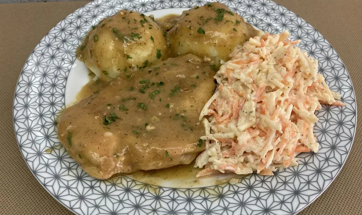 Pyszna pierś z kurczaka w sosie własnym, podana z purée ziemniaczanym i surówką z marchewki i kapusty.
