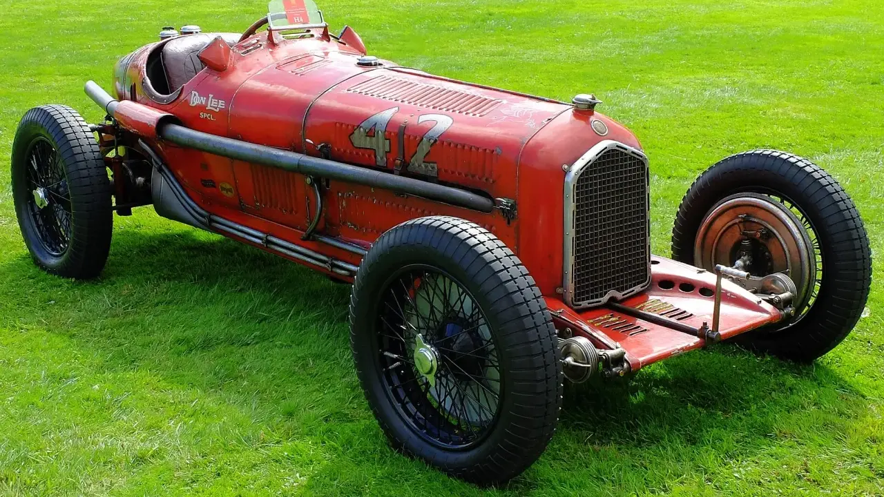 Roter Alfa Romeo P3 Rennwagen mit Nummer 42 fährt auf einer Straße, Fahrer mit Kopftuch.