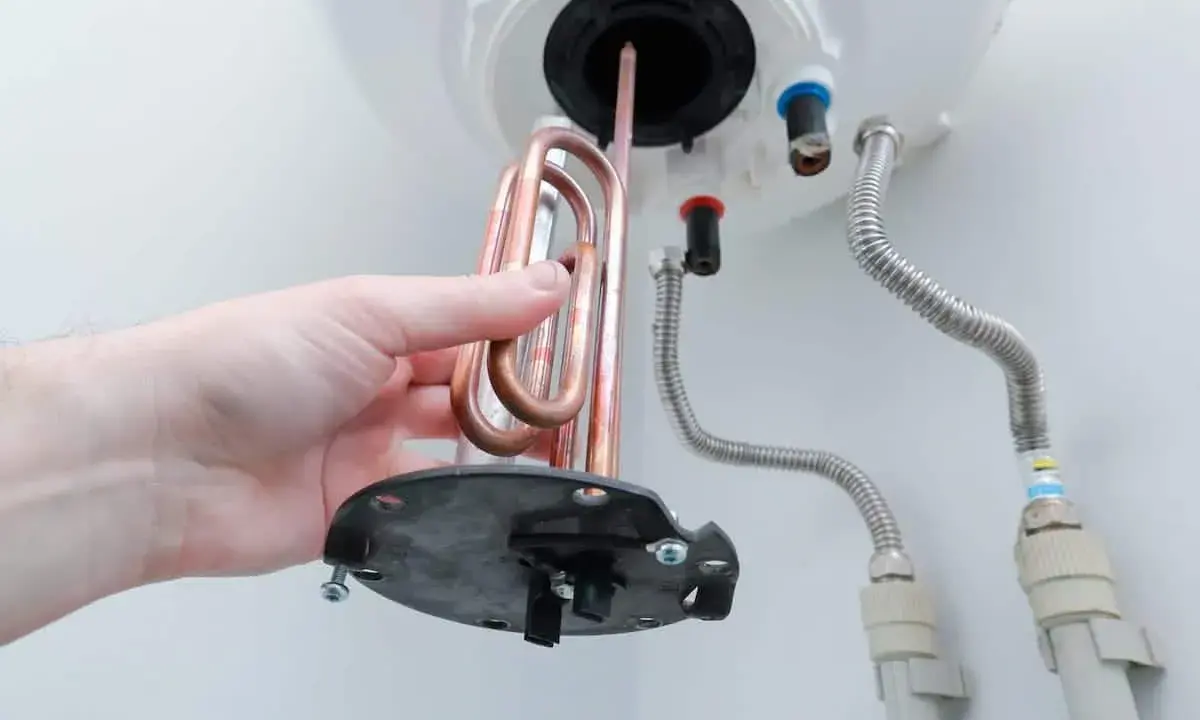 Mano retirando resistencia de cobre para saber como limpiar un termo por dentro.