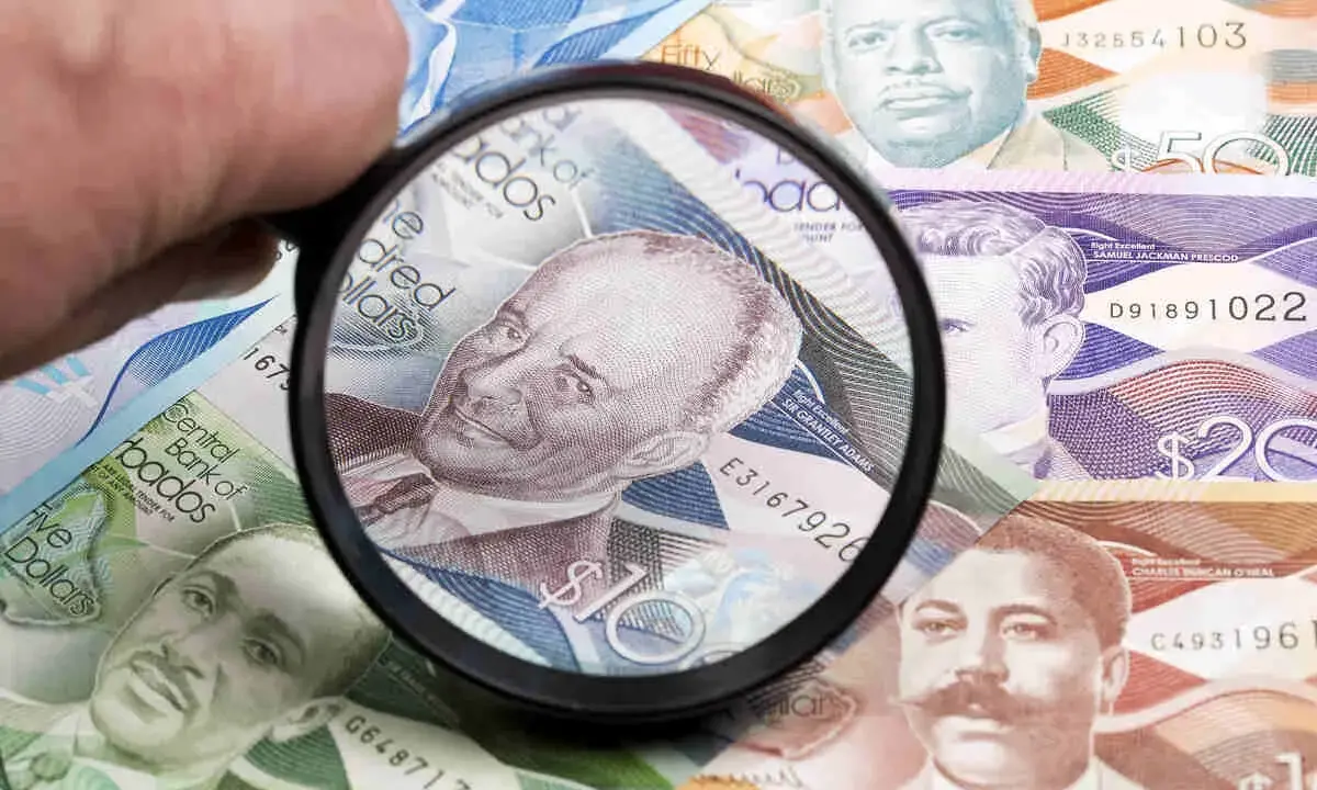 Förstoringsglas granskar sedlar med porträtt, visar Barbados valuta.