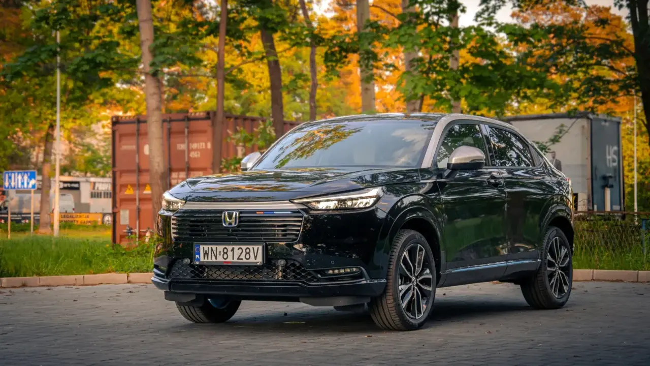 Elegancki, czarny Honda HR-V 2025 na tle jesiennych drzew i kontenerów.