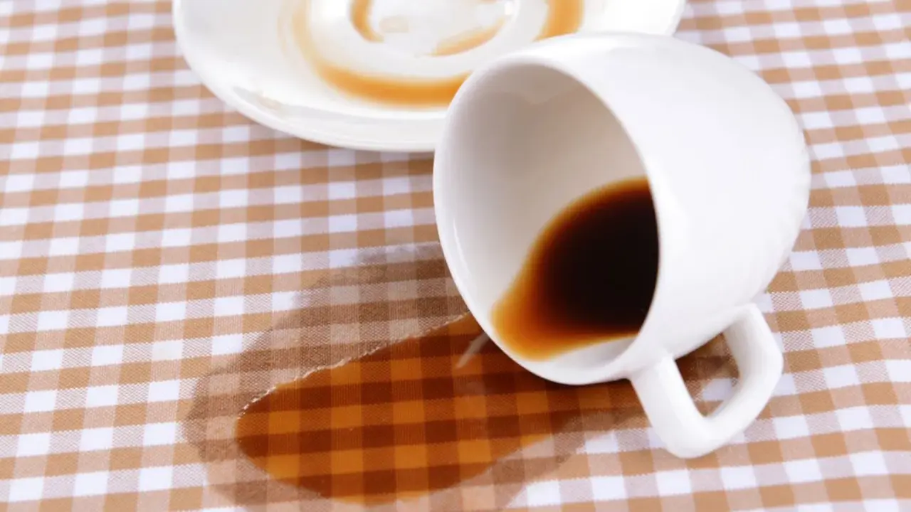 Um Kaffeeflecken aus Tischdecke zu entfernen, braucht es Geduld. Eine umgekippte Tasse hinterließ einen braunen Fleck auf kariertem Stoff.