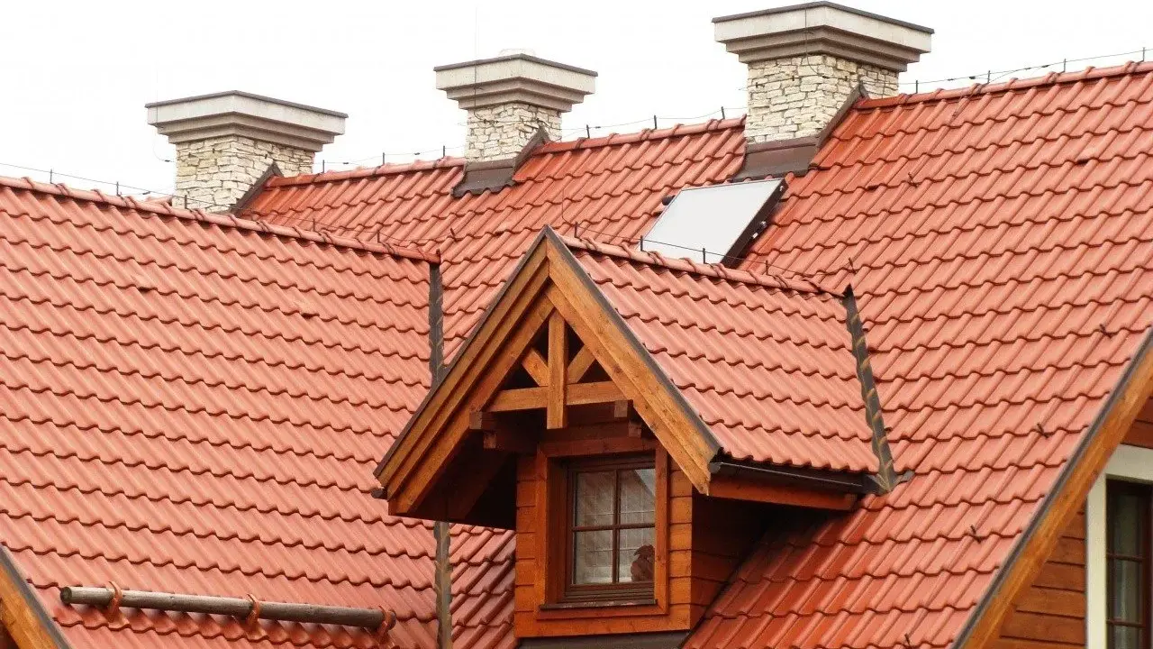 Dach dwuspadowy z czerwonej dachówki, z kominami i lukarną. Instalacja odgromowa zabezpiecza budynek.