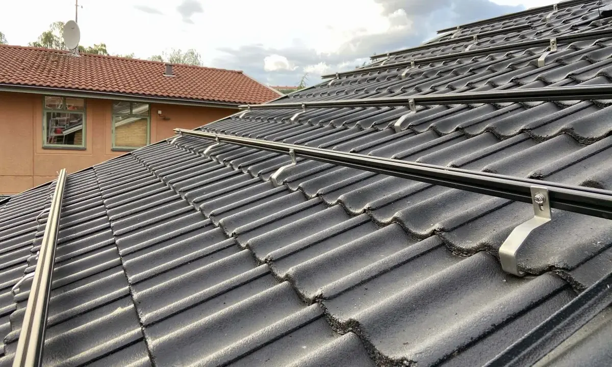 Solpaneler monteras på taket med hjälp av robusta aluminium skenor. Takpannorna är mörka och vågformade.