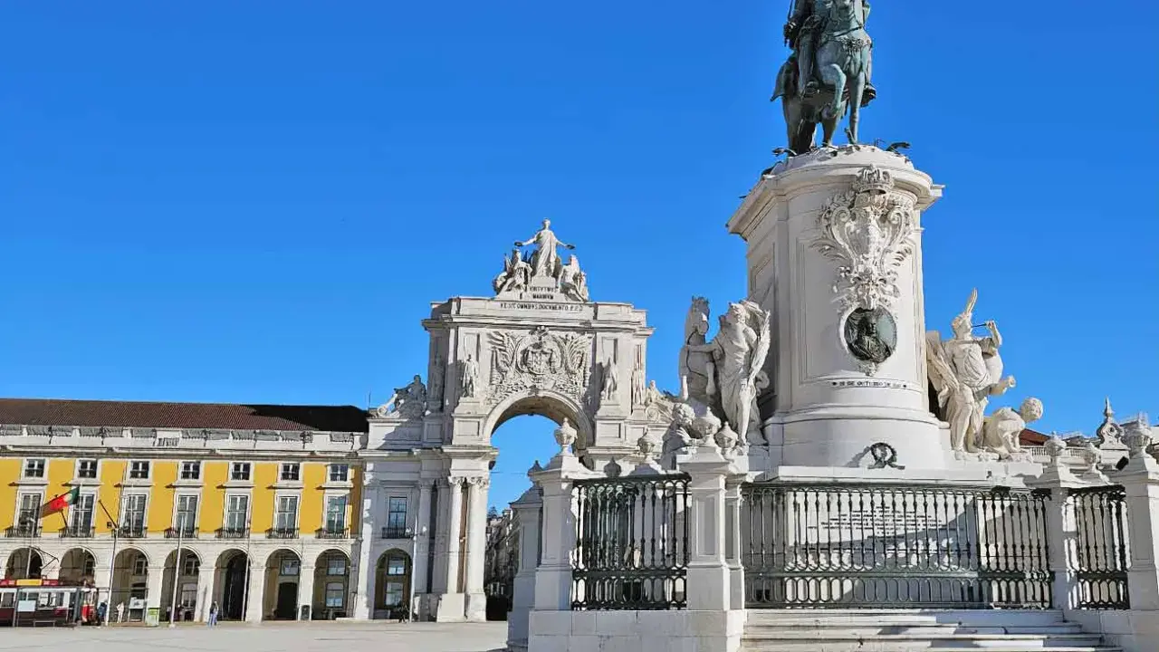 Reiterdenkmal und Triumphbogen am Praça do Comércio in **Baixa Lissabon** unter strahlend blauem Himmel.