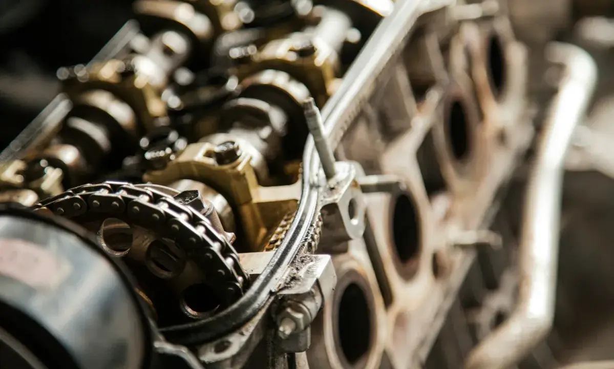 Zbliżenie na mechanizm rozrządu silnika samochodowego. Widoczny jest łańcuch rozrządu i koła zębate, które mogą wskazywać na objawy kończącego się rozrządu.