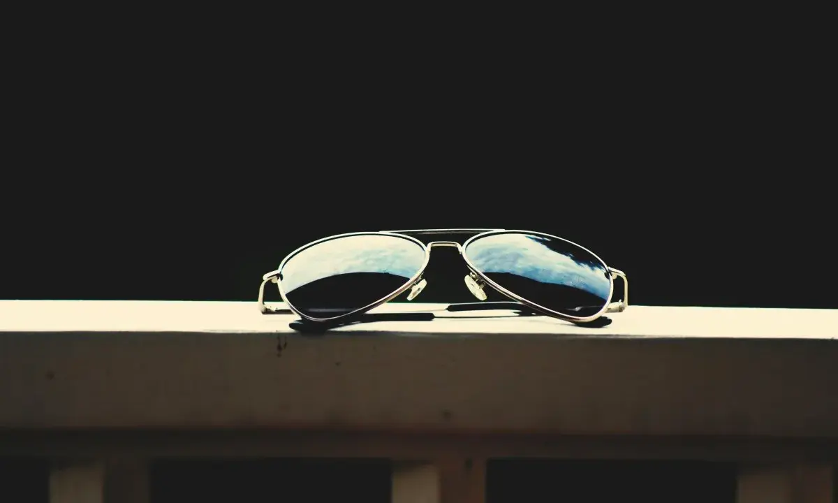 Okulary przeciwsłoneczne typu aviator leżące na drewnianej powierzchni.