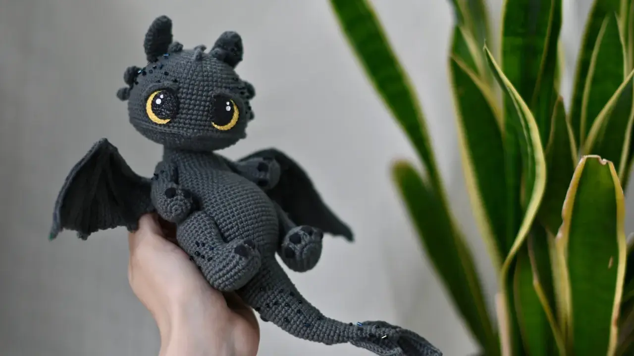 Adorable dragón amigurumi gris con ojos amarillos brillantes. ¡Encuentra el dragon amigurumi patron gratis en español para crear el tuyo!