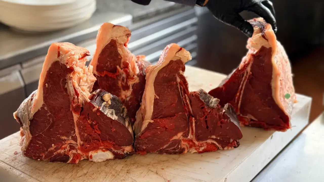 Maneggiare con cura la bistecca fiorentina a Firenze, pronta per essere grigliata.