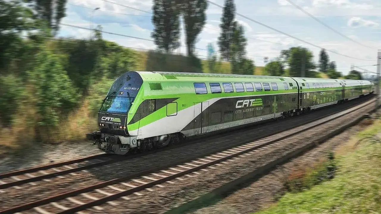 Grön och vit CAT City Airport Train susar fram på spåret, på väg till flygplatsen i Wien.