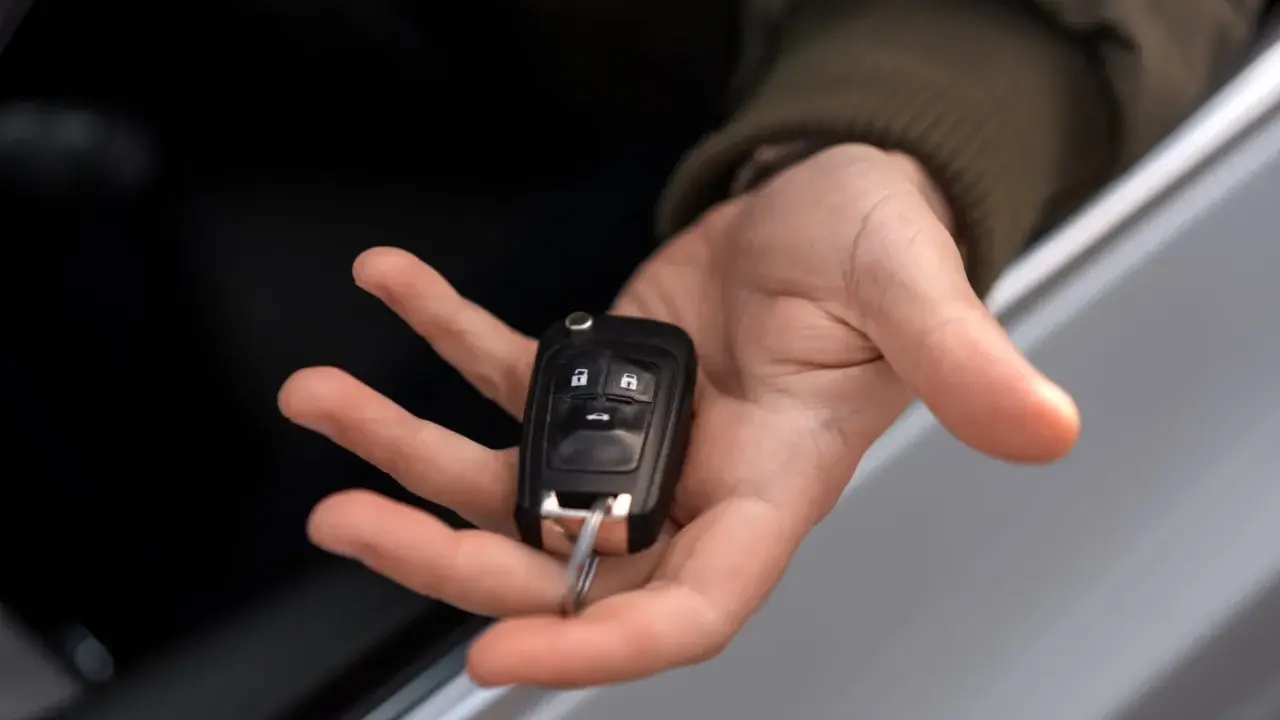 Mano sosteniendo una llave de coche moderna, lista para codificar y arrancar.