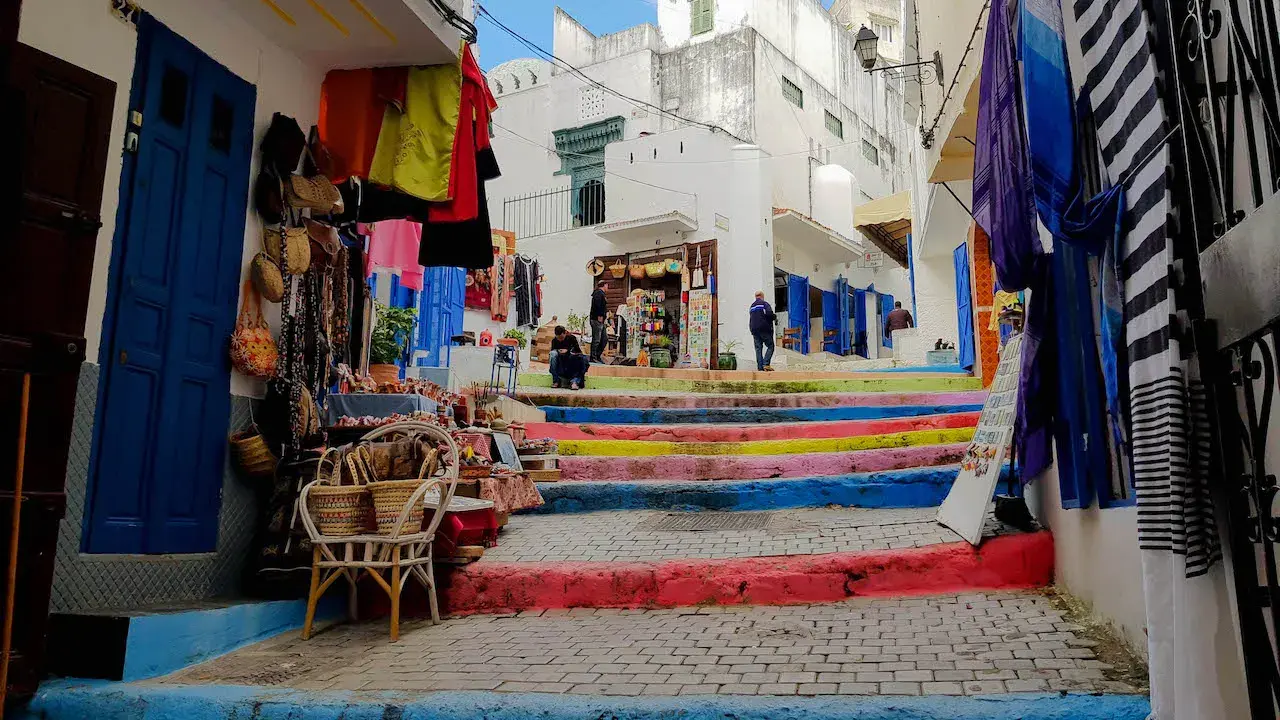 Bunte Treppe in Tanger, wo Frauen in bunten Gewändern Souvenirs verkaufen.