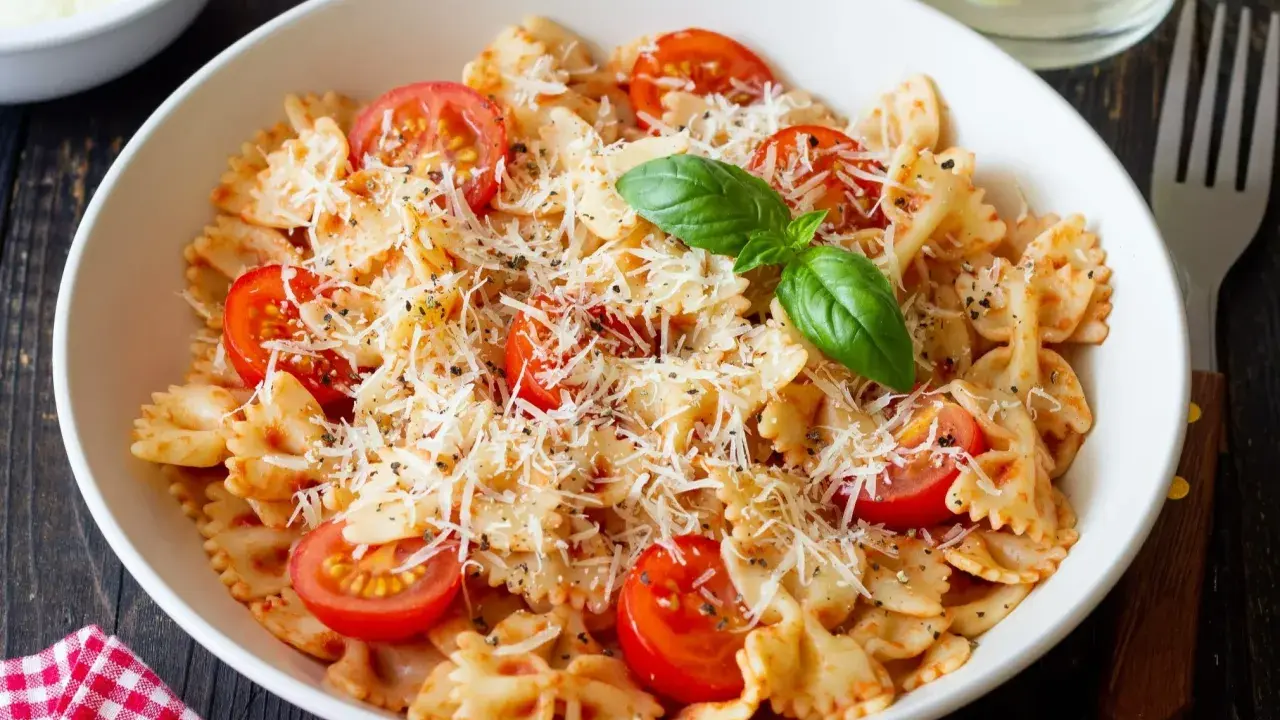 Pyszny makaron farfalle z pomidorkami koktajlowymi i parmezanem, idealny na kolację.