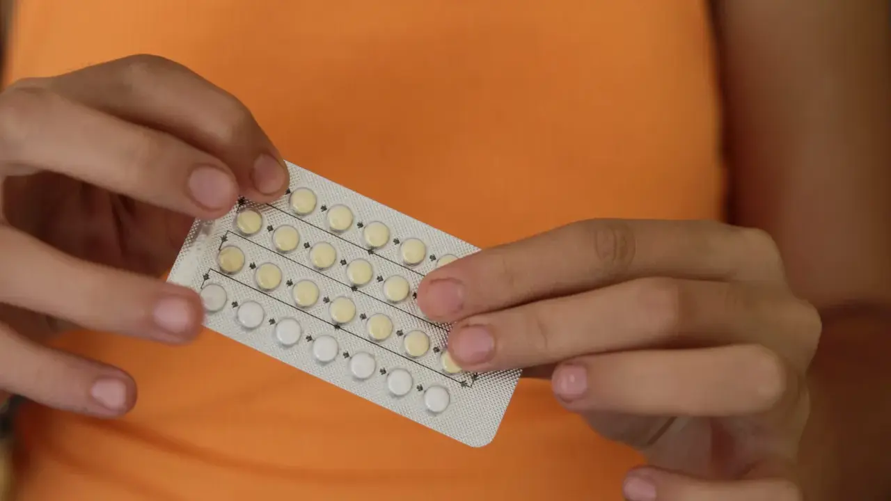 Manos sostienen un blíster de pastillas anticonceptivas. Me he quitado el anillo y no me baja la regla, ¿será por esto?