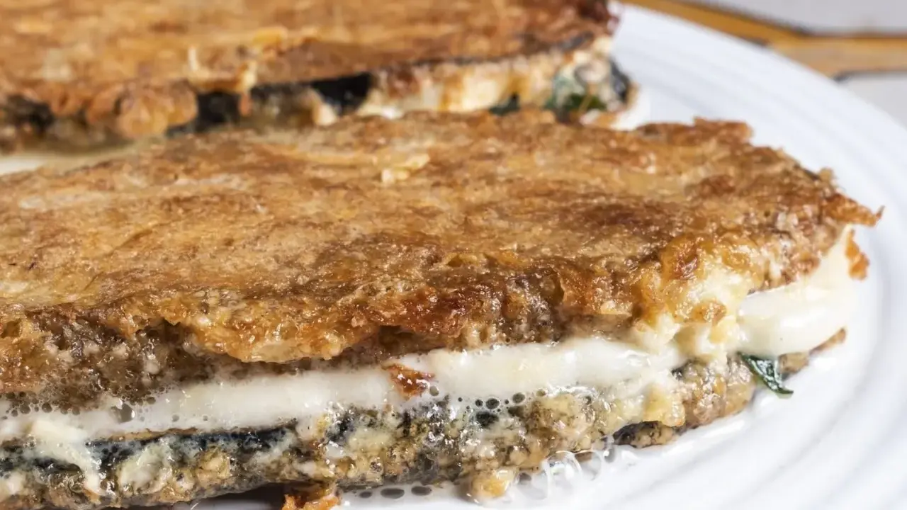 Parmigiana di melanzane ricetta originale: strati dorati e filanti di melanzane fritte, mozzarella e sugo.
