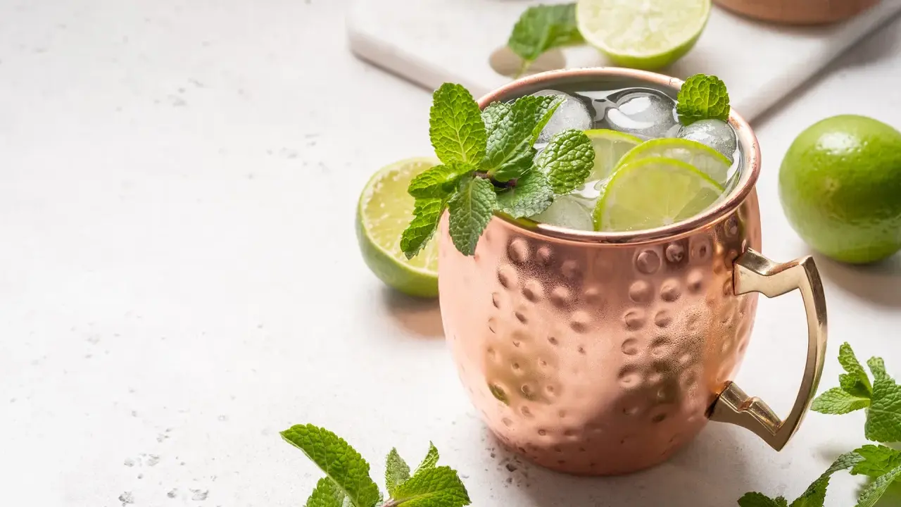 Erfrischender Moscow Mule in Kupferbecher mit Limettenscheiben, Minze und Eis. Perfekt für warme Tage und verschiedene rum sorten.