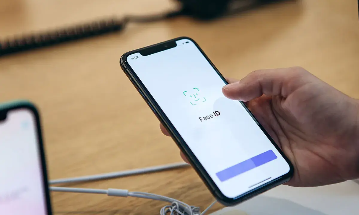 Dłoń trzyma iPhone'a z włączonym ekranem Face ID.