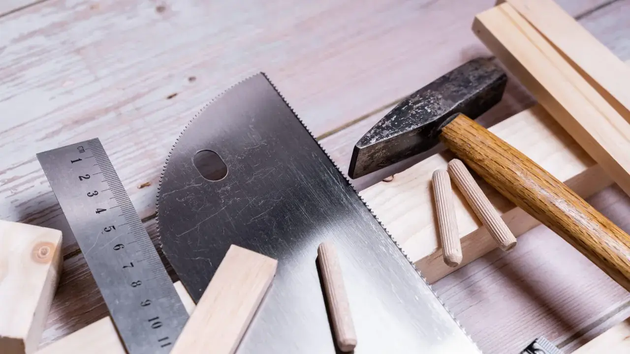Herramientas para trabajar la madera: sierra, martillo, regla y tacos de madera listos para un proyecto.