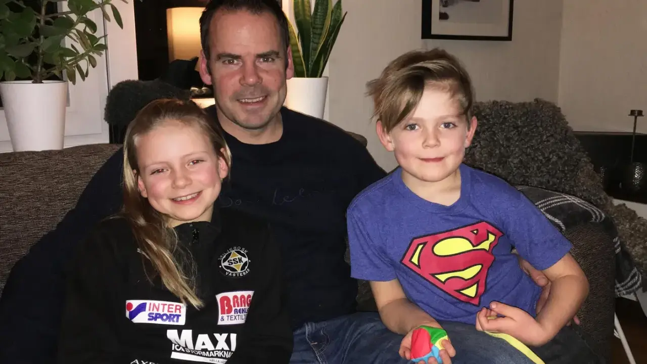 Marcus Oscarsson med sin familj, dottern och sonen sitter glatt i soffan.