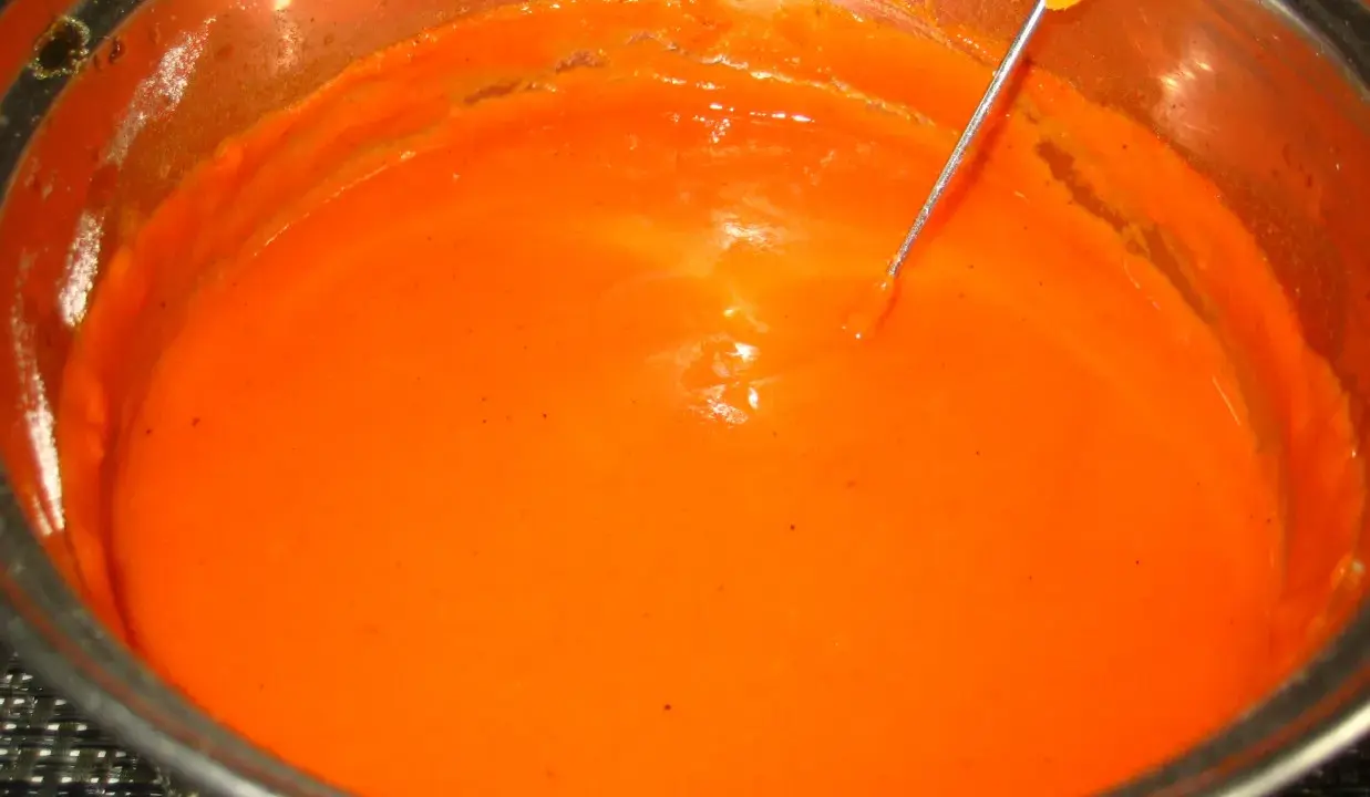 Gęsty, pomarańczowy sos pomidorowy do gołąbków w metalowym garnku, z widoczną igłą termometru.