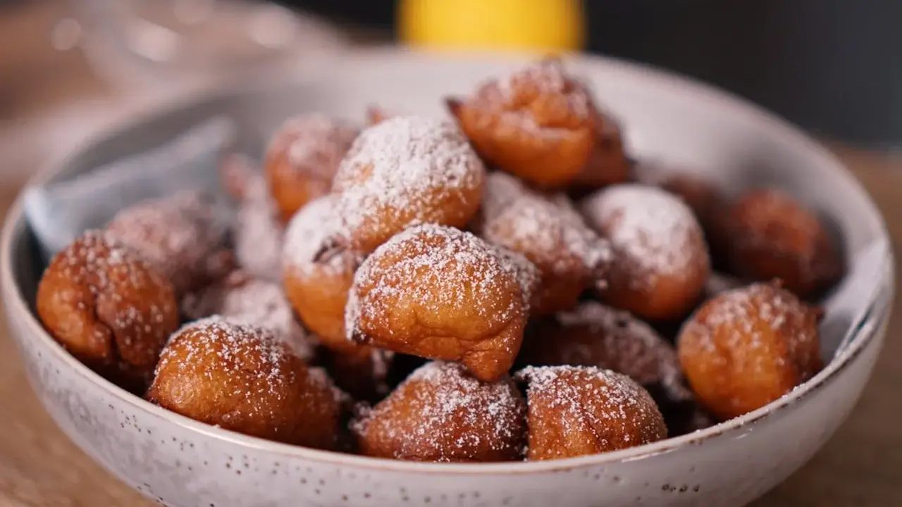 Un bol rempli de beignets dorés, saupoudrés de sucre glace. Parfait pour une recette beignet moelleux rapide.