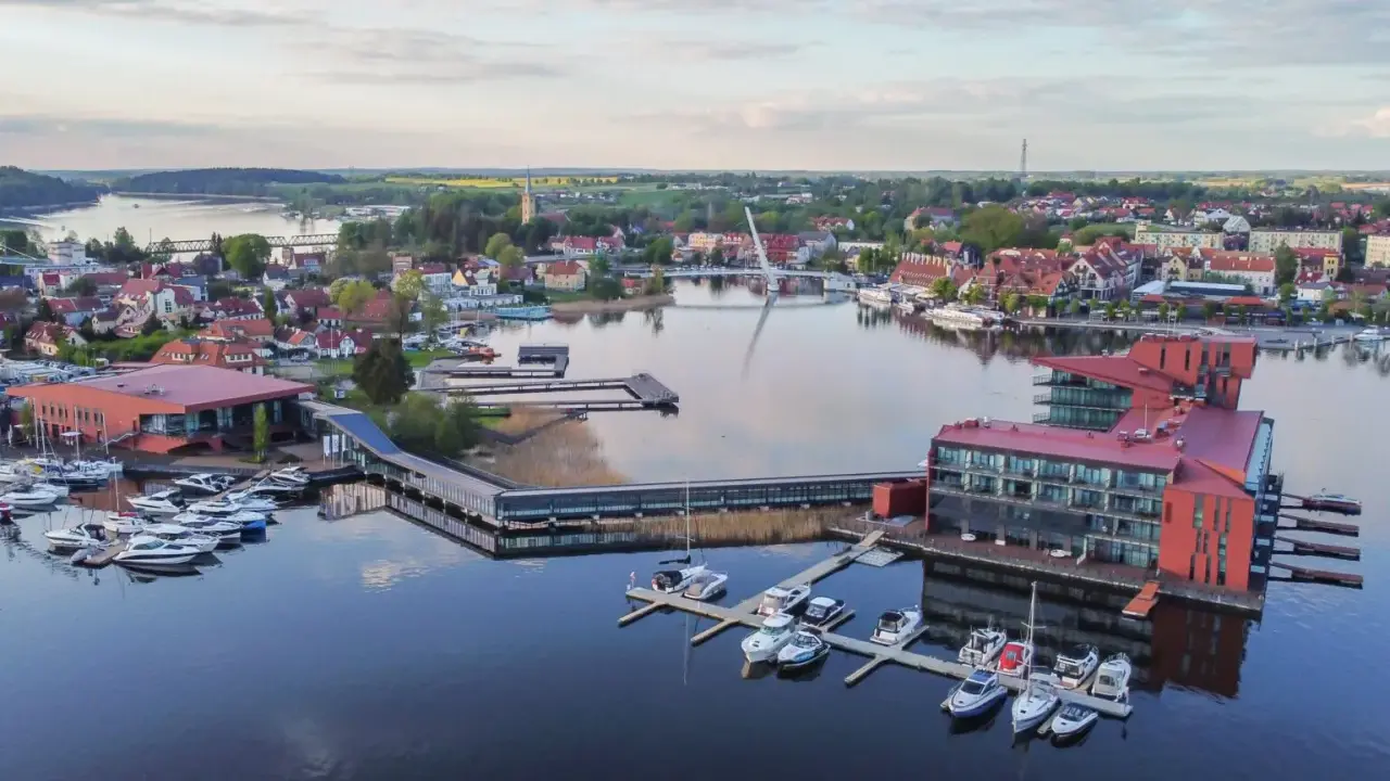 Nowoczesna marina i hotel na Mazurach. Widać tu liczne łodzie, nowoczesną architekturę i malowniczy krajobraz, idealne mazury atrakcje.
