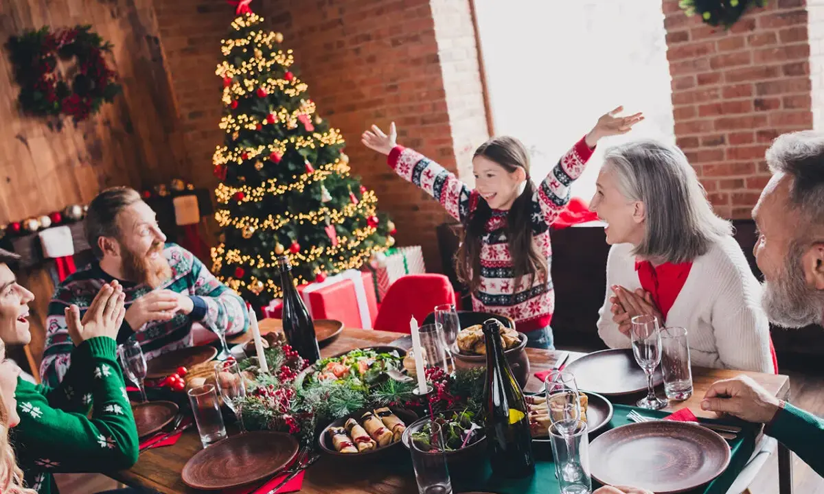 Familia celebrando Navidad en España con niños. Árbol decorado, mesa puesta y regalos. ¡Un plan perfecto donde ir en navidad en españa con niños!