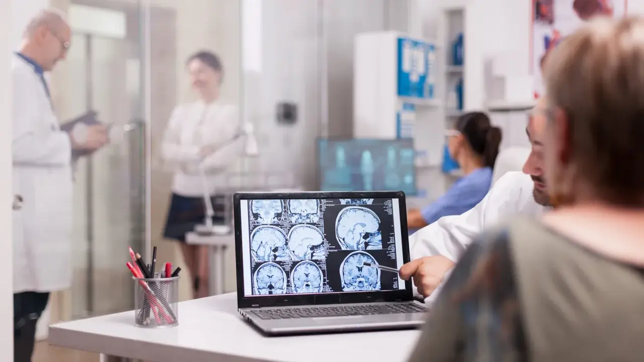 Medico mostra scansioni cerebrali, discutendo le possibili memoria a breve termine cause con un paziente.