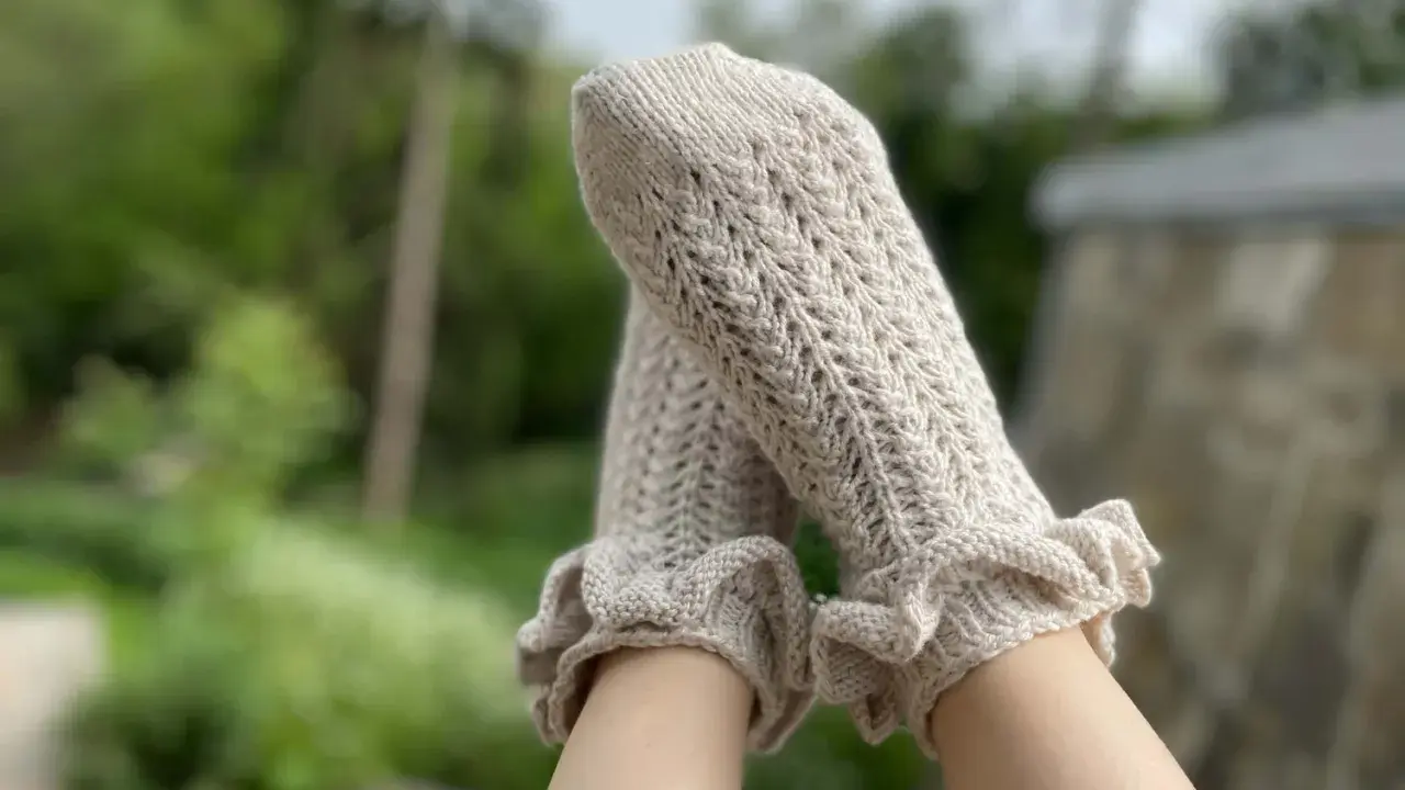 Piernas con calcetines de crochet color crema, con volantes en los tobillos y un delicado patrón calado.