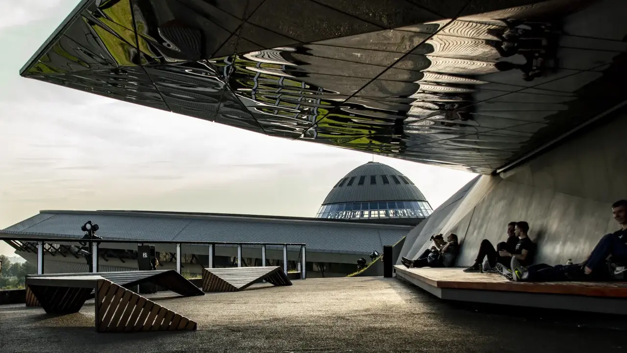 Nowoczesna architektura i ludzie odpoczywający pod zadaszeniem. W tle kopuła Muzeum Śląskiego, jedna z głównych katowice atrakcje.